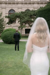 Braut nähert sich dem Bräutigam beim First Look am Maria-Theresien-Platz