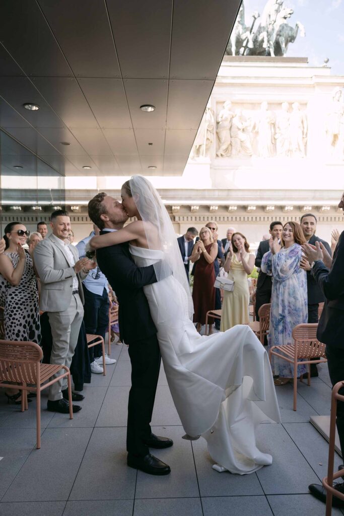 Bräutigam hebt die Braut und küsst sie beim Auszug nach der Trauung am Österreichischen Parlament